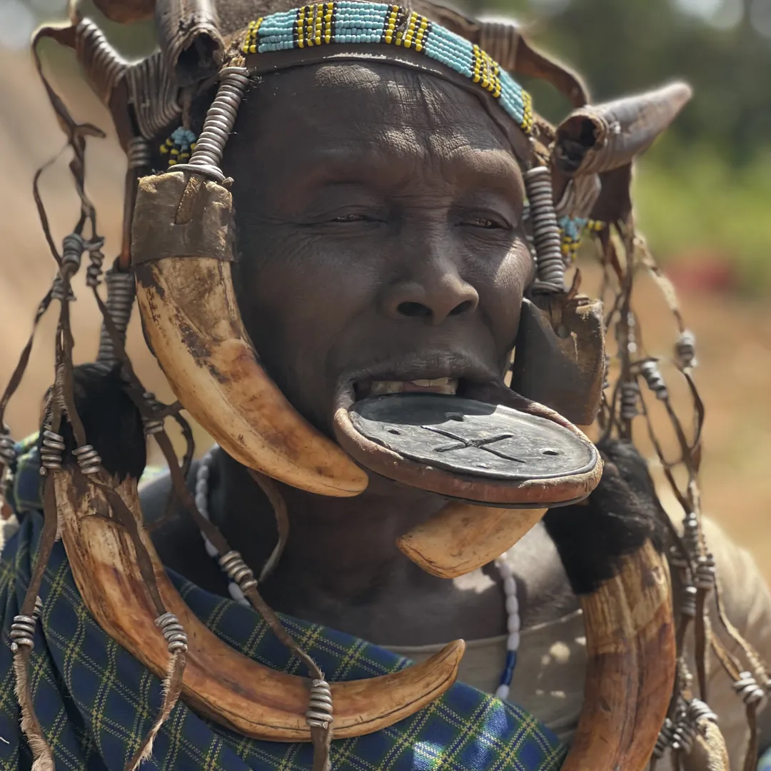Ritratto di un membro della tribù Mursi in Etiopia, che mostra un piattello labiale tradizionale e ornamenti con zanne di facocero.