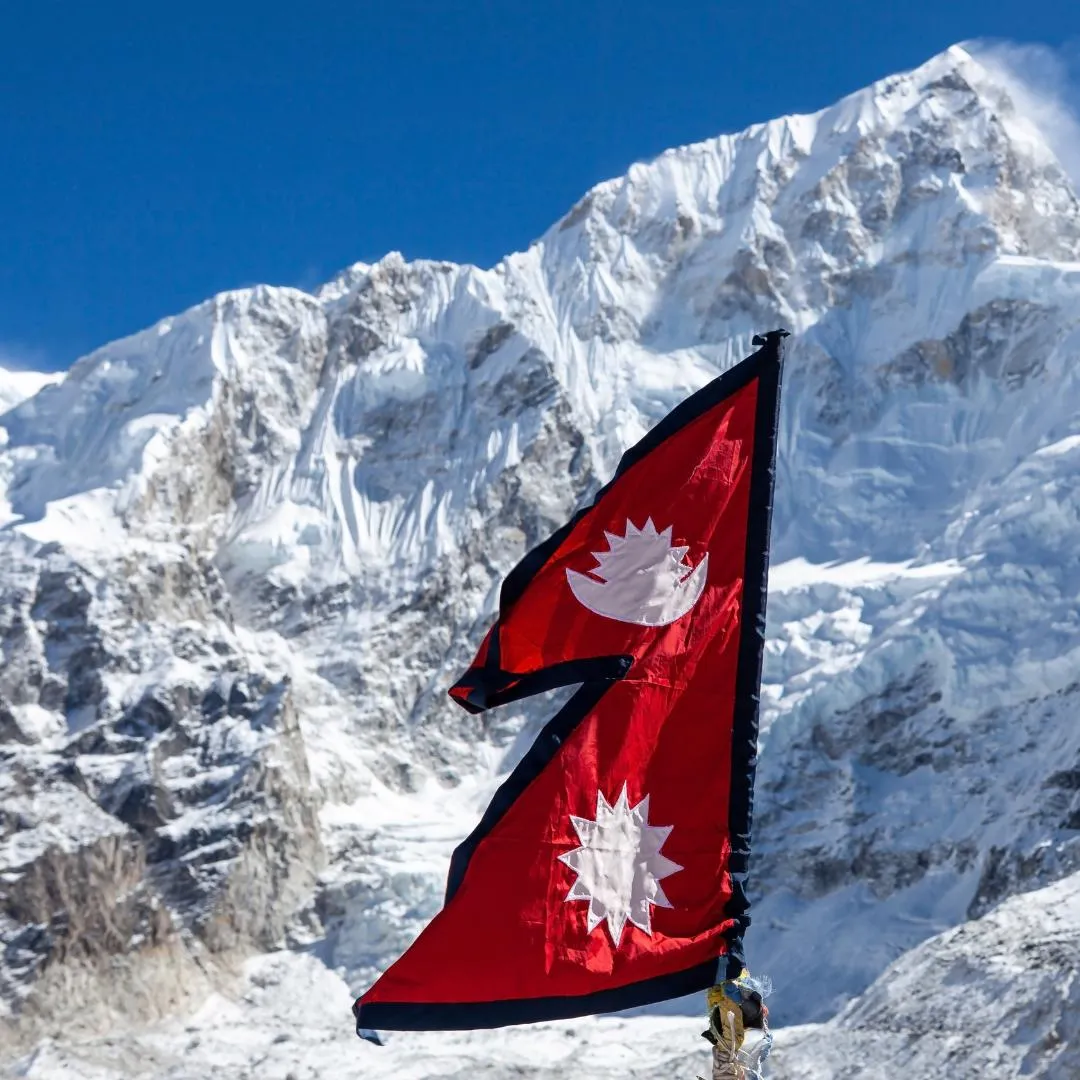 Bandierine di preghiera tibetane colorate appese a fili contro un cielo blu limpido, vicino a uno stupa a Katmandu Nepal, durante un tour organizzato.