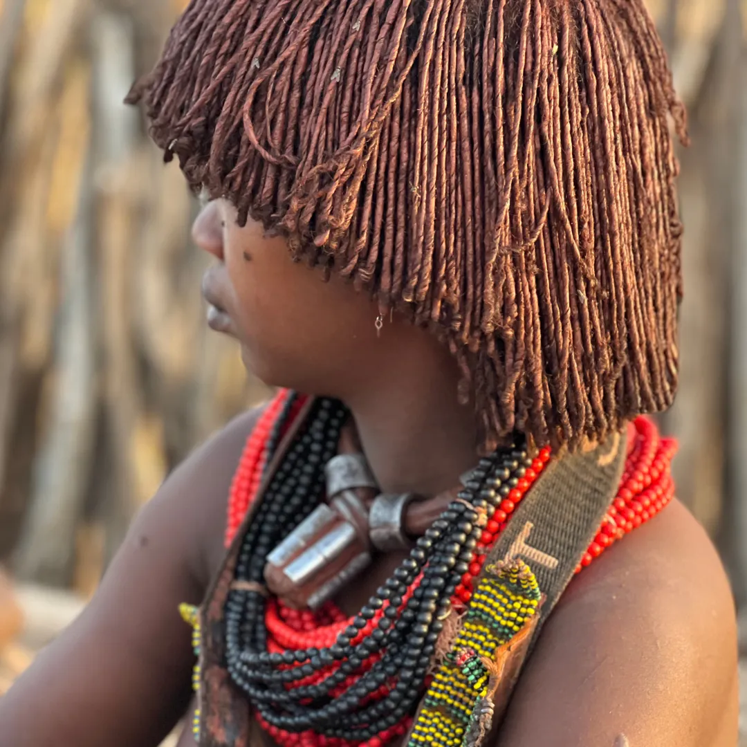 Primo piano di una donna della tribù Hamer in Etiopia, con l'acconciatura tradizionale e collari di perline.