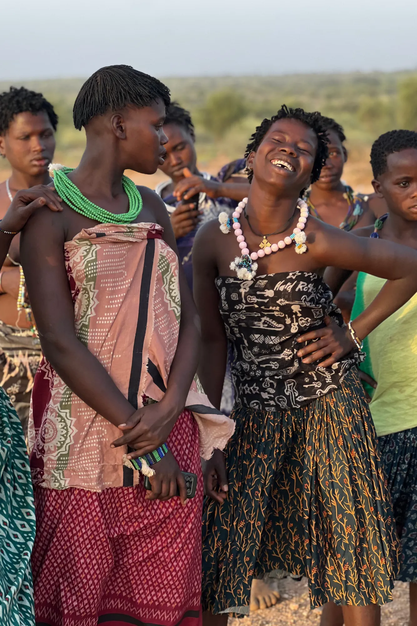 Un gruppo di giovani donne della tribù Hamar che ridono insieme con acconciature tradizionali in ocra e collane di perline nella Valle dell'Omo, in Etiopia.