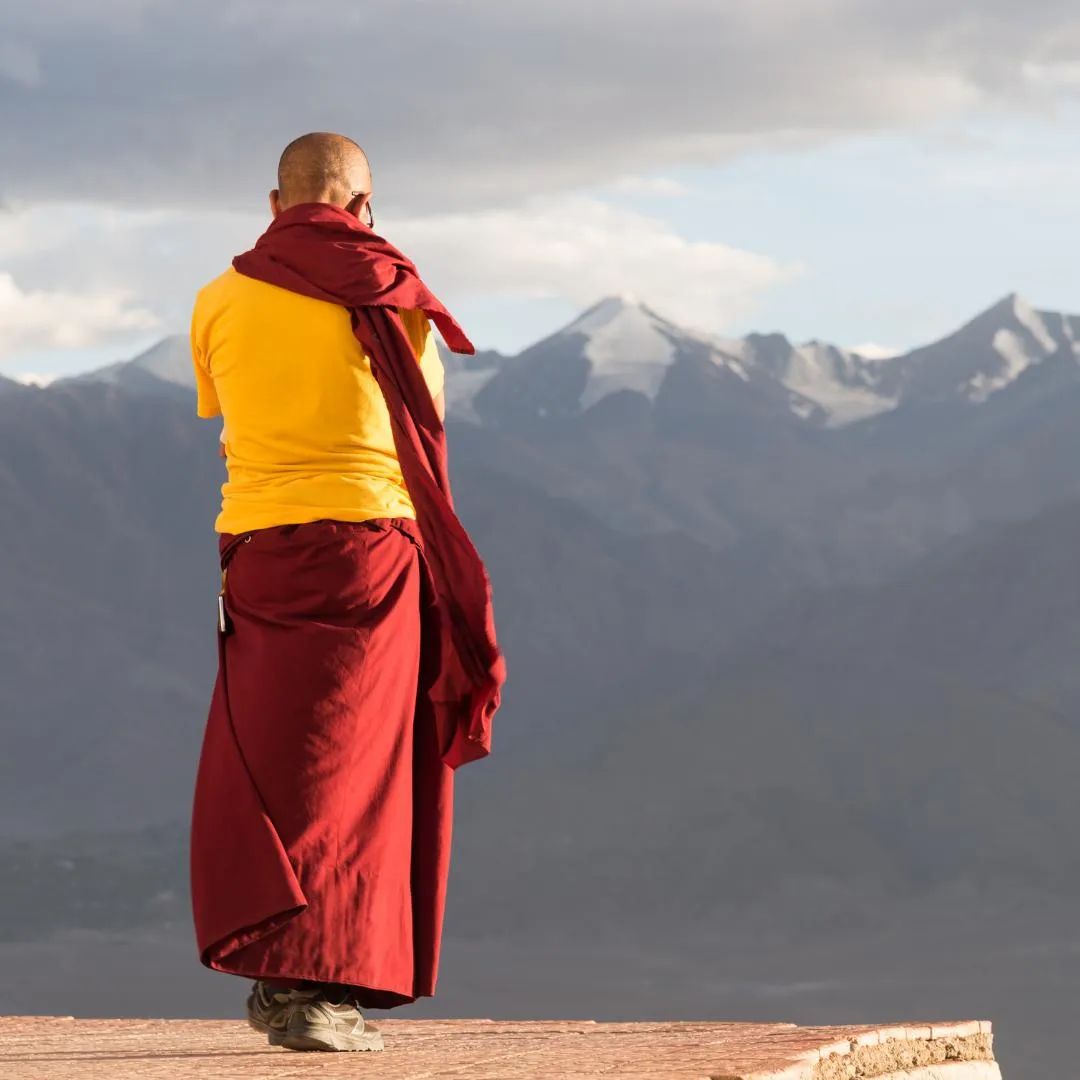Monaco tibetano di spalle che ammira le cime montuose dell'Himalaya durante un'escursione di trekking in Nepal.