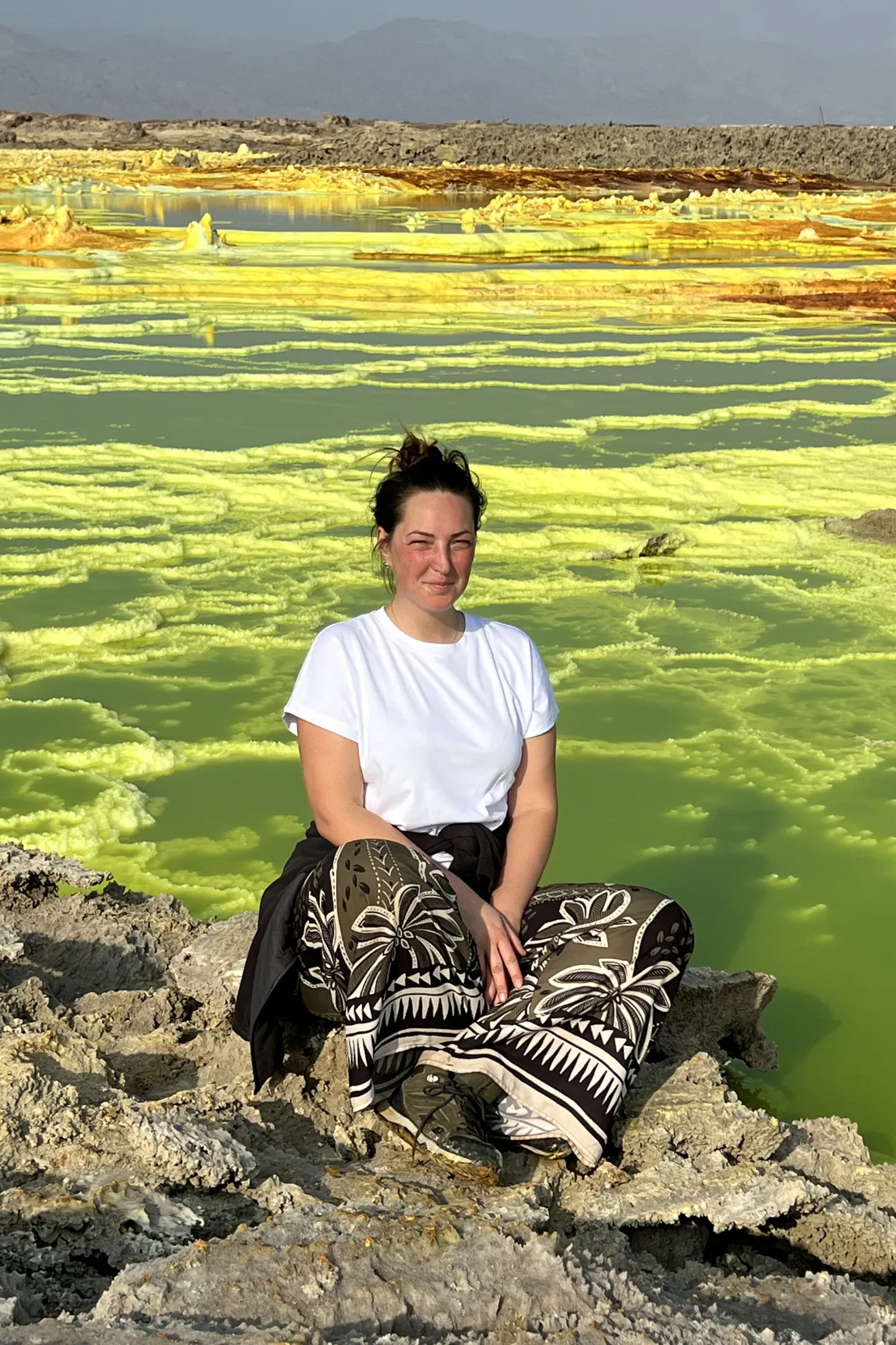 ritratto di una viaggiatrice Yagiu seduta davanti alle spettacolari sorgenti gialle del vulcano Dallol nella depressione della Dancalia, in Etiopia.