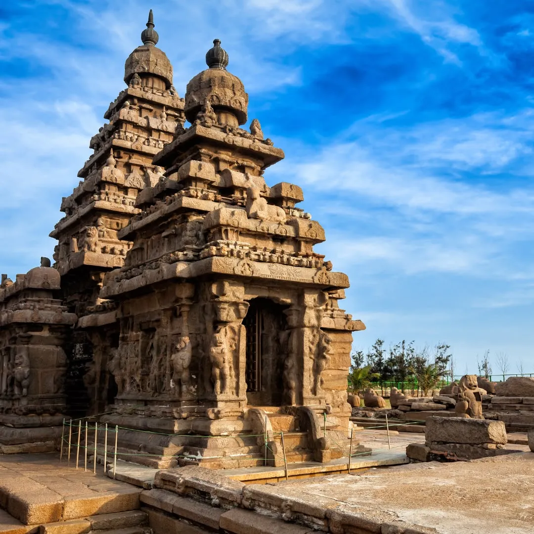 Antico tempio in pietra di Mahabalipuram con due torri scolpite sotto un cielo blu con nuvole.