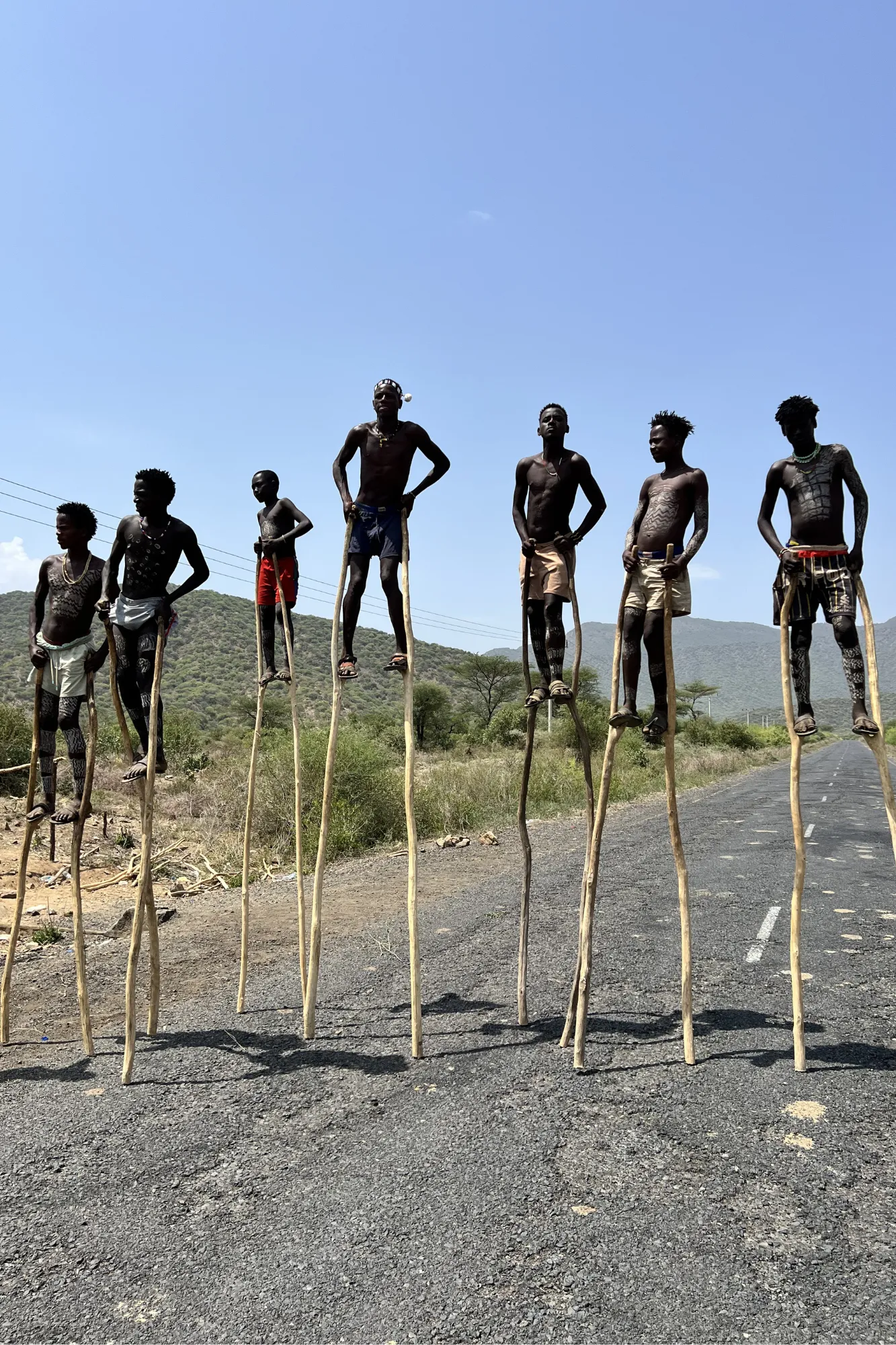 Giovani ragazzi della tribù Banna camminano su alti trampoli di legno tradizionali nella Valle dell'Omo in Etiopia.