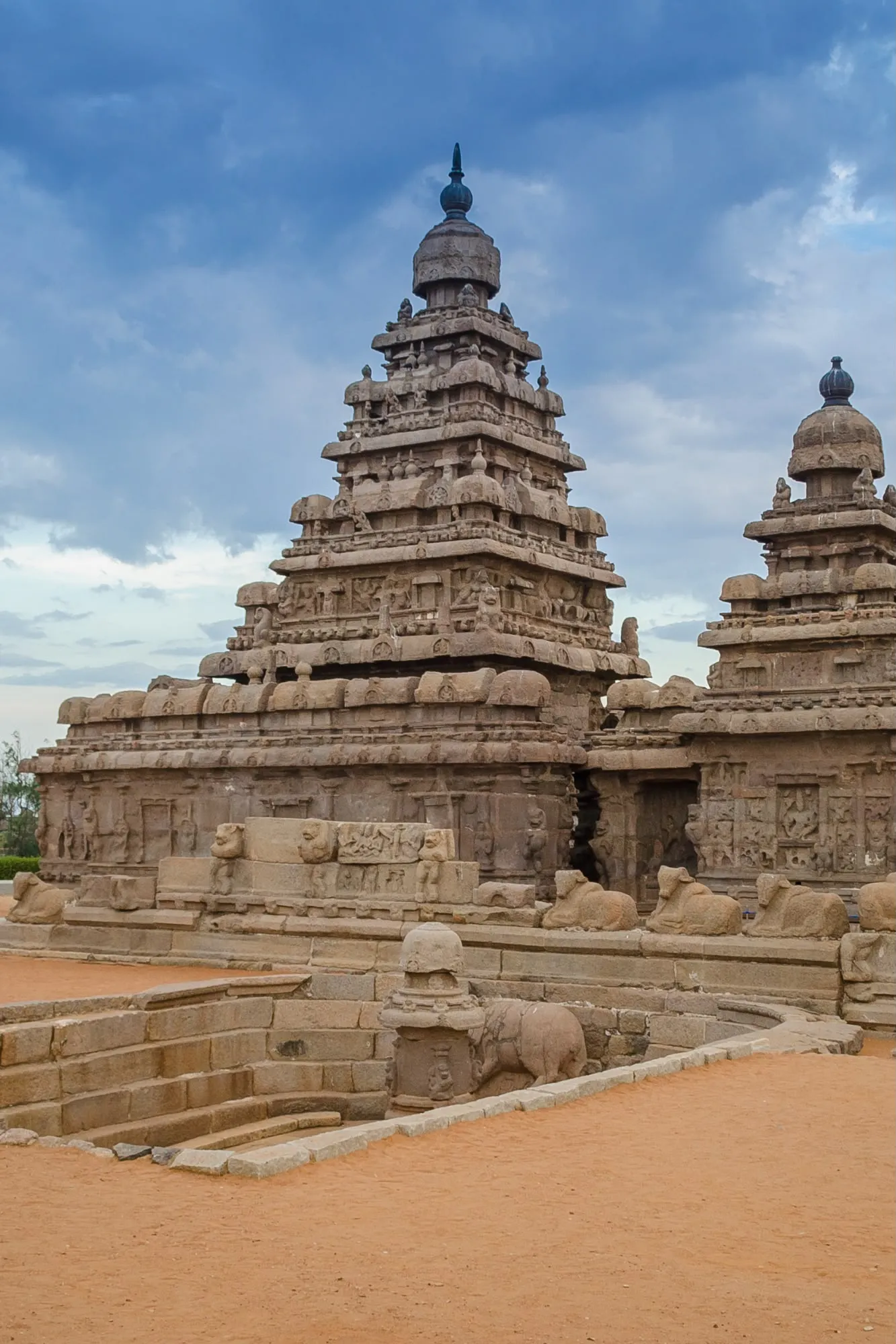 Il Tempio della Spiaggia a Mahabalipuram in pietra arenaria protetto da un muretto con statue di toro distese.