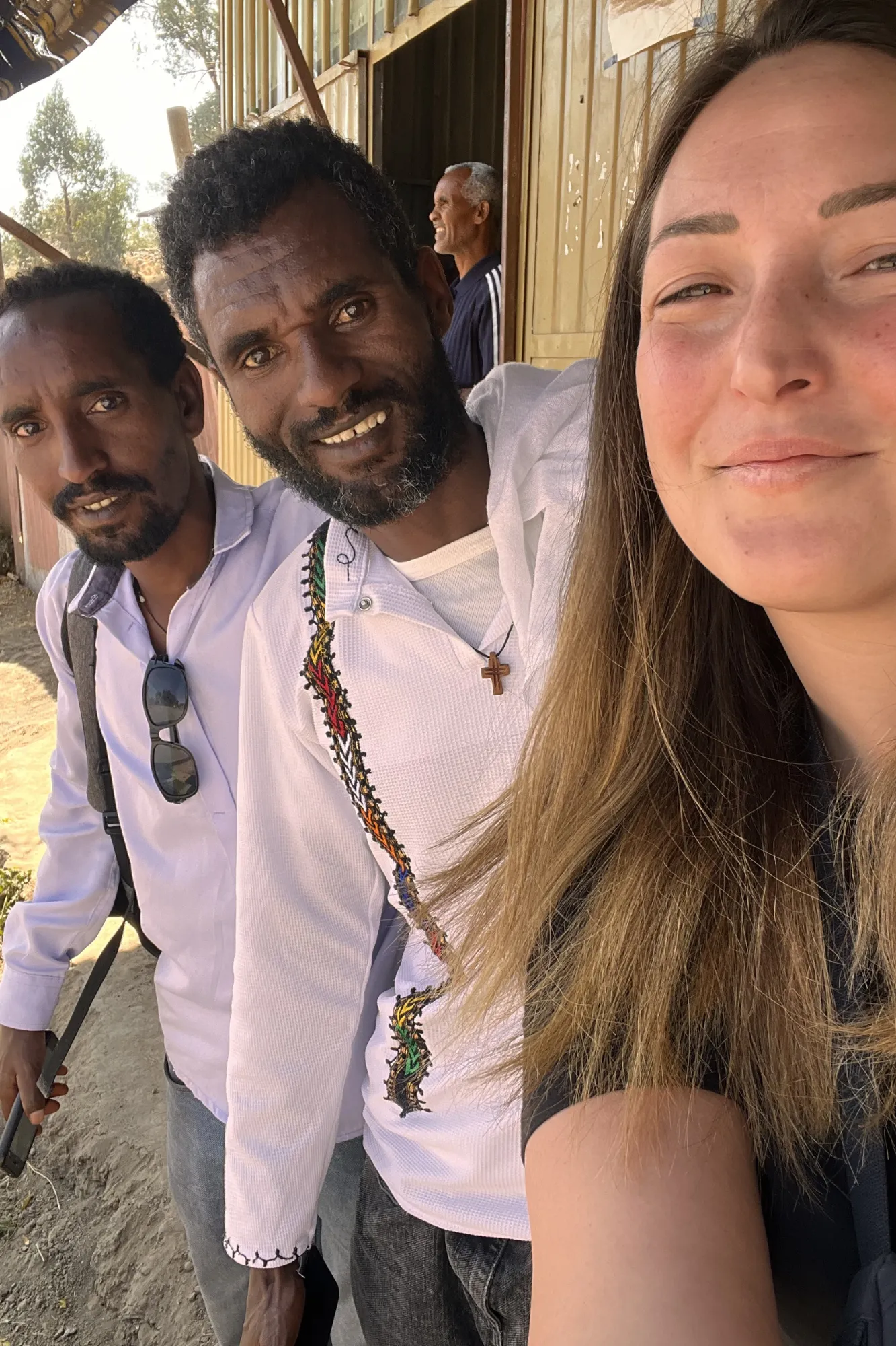 Selfie di una viaggiatrice Yagiu insieme a due uomini locali sorridenti durante un tour culturale a Lalibela, in Etiopia.