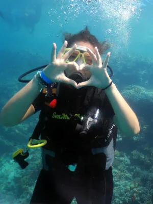 Ragazza subacquea fa il segno del cuore con le mani durante un'immersione nel Mar Rosso