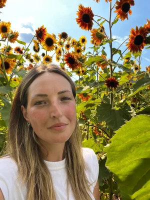 Selfie in primo piano di una ragazza all'interno di un fitto campo di girasoli alti sotto il sole