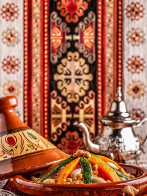 Piatto tipico di tajine di verdure con couscous e teiera marocchina sullo sfondo