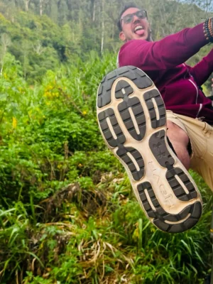 Ragazzo scherza mostrando la suola della scarpa da trekking durante un'escursione nella foresta