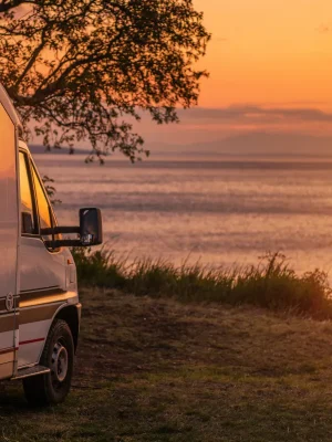 Camper parcheggiato sulla costa al tramonto durante un viaggio on the road organizzato